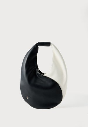 Soft leather handbag in black and white with a yin-yang design and a zip closure along the curved seam, set against a plain background.