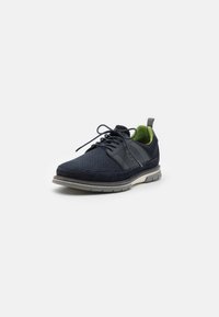 Navy mesh and suede sneaker with a textured side panel, green inner lining, and a light gray rubber sole. Features laces and a back loop.