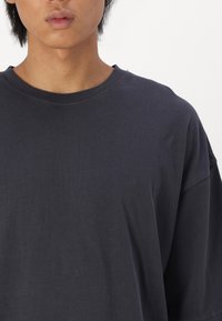 Mørkegrå bomulds t-shirt med rund udskæring, korte ærmer og synlige syningsdetaljer, der har en blød tekstur og en afslappet pasform.