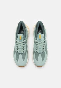 Light green sneakers with mesh and synthetic upper, rubber sole, padded collar, and contrasting yellow branding on the tongue.