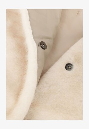 Light beige leather jacket interior with white shearling lining, featuring black snap buttons and soft texture.