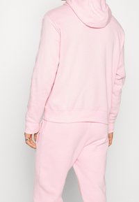 Ljusrosa hoodie i mjuk, texturerad fleece med stor huva och ribbade muddarna, i kombination med matchande sweatpants.