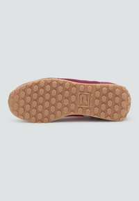 Suela de una zapatilla roja con un patrón de tracción hexagonal marrón y la marca "PATRICK" centrada en la suela.