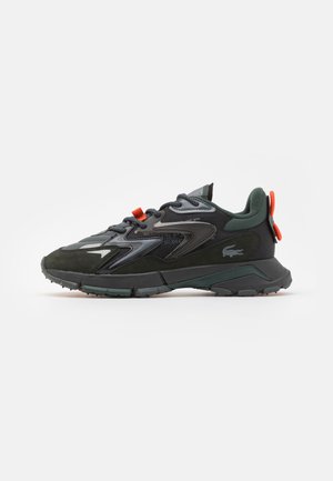 Schwarze Sportschuhe mit Details aus Mesh und Wildleder, reflektierenden Akzenten und einer robusten Sohle. Mit einem orangefarbenen Zugband und Logo-Branding.