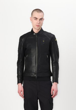 Zwarte leren jas met een ritssluiting aan de voorkant, geribbelde accenten op de schouders en een ritszak. Glad materiaal en aangesloten ontwerp.