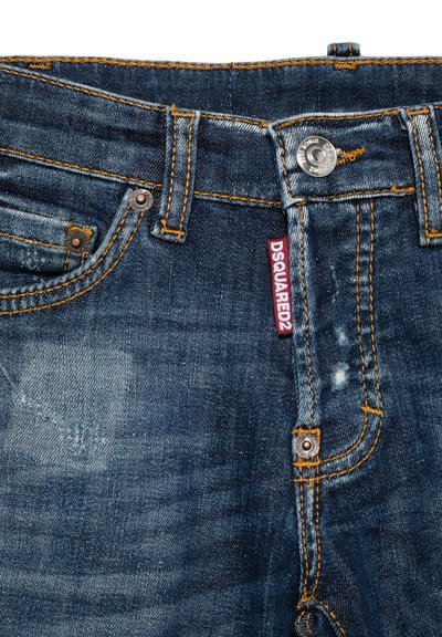 Jeans in denim blu scuro presentano cuciture arancioni a contrasto, una chiusura con bottone frontale e un'etichetta del marchio visibile sulla vita.