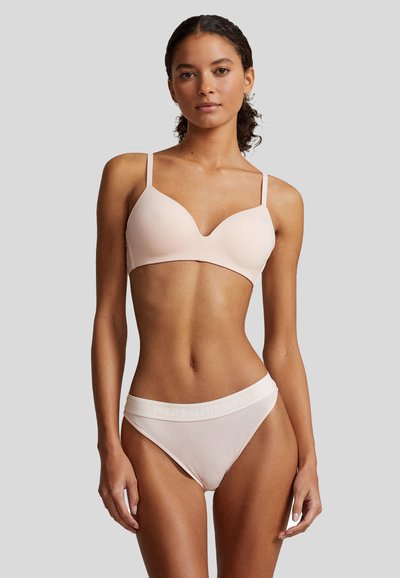 Világos rózsaszín, varrat nélküli bralette vékony pántokkal, mély V-dekoltázzsal. Hozzáillő bordázott bikini logóval ellátott derékkal. Sima anyagú textúra.