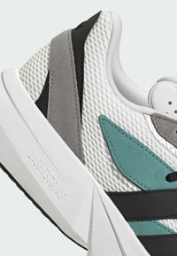 Mesh-Sneaker mit weißem Obermaterial und Akzenten in Türkis, Grau und Schwarz. Auffällige strukturierte Details und eine klobige weiße Sohle mit der Aufschrift "LIGHTSTRIKE".