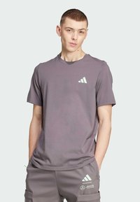 Camiseta gris de manga corta hecha de material suave que presenta un diseño minimalista con un pequeño logo verde claro en la parte izquierda del pecho.