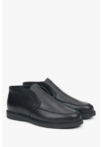 Zwarte leren schoenen met een gladde afwerking, met een instapontwerp, ronde neus en lage rubberen zool. Stiksel details aan de zijkant.
