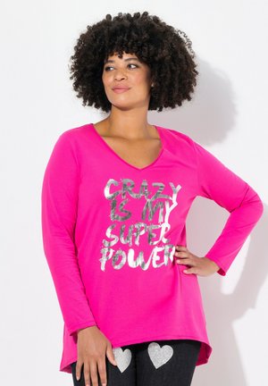Rosa Langarmshirt mit V-Ausschnitt, versehen mit silbernem Text, der "CRAZY IS MY SUPER POWER" liest. Weicher Stoff mit lockerer Passform.