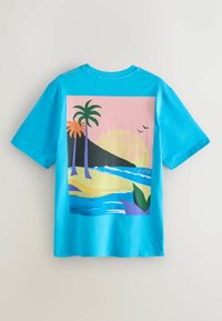 T-shirt bleu vif arborant une scène de plage colorée avec des palmiers, des vagues, un soleil couchant, des oiseaux et des collines lointaines.