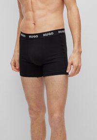 Zwarte boxershorts met een nauwsluitende pasvorm, gemaakt van rekbare stof. Heeft een zwarte tailleband met witte "HUGO"-logo en een platte naadontwerp.