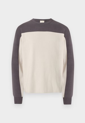 Suéter de manga larga con cuello redondo, con hombros y mangas en gris oscuro, y cuerpo en beige claro, mostrado sobre un fondo blanco.