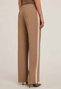 Bruine wijde broek met crèmekleurige zijkanten, voorzien van een riem in de taille en een gladde textuur. De silhouet is ontspannen en goed afgewerkt.