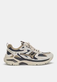 Sneaker bézs, tengerészkék és barna színkombinációval, hálós és velúr anyagokból, párnázott talppal és jellegzetes hullámos díszítéssel az oldalán.