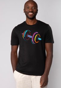 Schwarzes T-Shirt mit einem bunten Grafik-Motiv eines Hantel. Die Hantel zeigt konzentrische Kreise in verschiedenen Farben um eine silberne Stange.