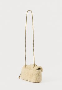 Bēšs, pūkains tekstūras somiņa ar taisnstūrveida formu un zelta ķēdes siksniņu. Mīksts materiāls ar smalku spīdumu un augšpusē salocītas detaļas.