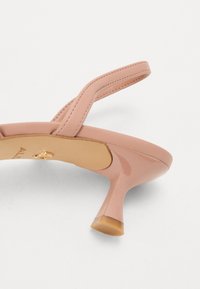 Sandale en cuir verni rose avec des brides fines et un talon stiletto bas élégant. Présente une surface lisse et un logo doré sur la semelle intérieure.