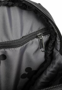 Interno nero di una borsa con una tasca con zip. Il tessuto testurizzato presenta un sottile motivo grigio. Bordo arrotondato e tessuto arricciato all'apertura.