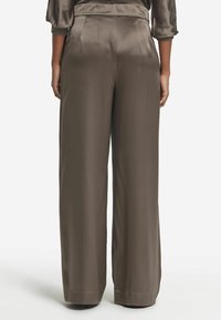 Vidbyxa i mörkbrun satin med en slät yta, med hög midja och sidofickor. Snygga veck sträcker sig från midjan.