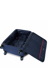 Maleta azul marino con un zipper abierto, que cuenta con cuatro ruedas, correas interiores y un bolsillo de acento rojo con forro de malla.