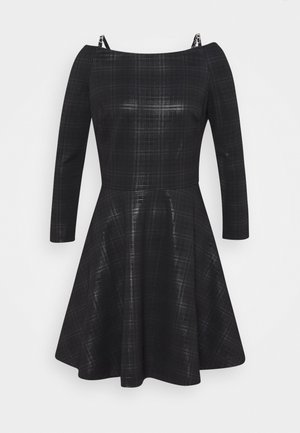 Robe à carreaux noirs à épaules dénudées avec manches longues, corsage ajusté, jupe évasée et fines bretelles sur un fond uni.
