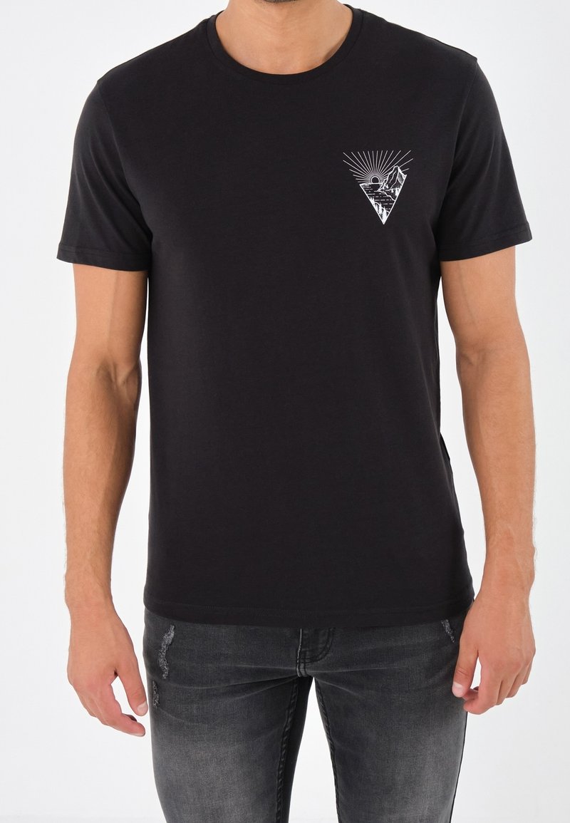 Camiseta de algodón negra con mangas cortas, cuello redondo y un diseño gráfico triangular blanco en el lado izquierdo del pecho.