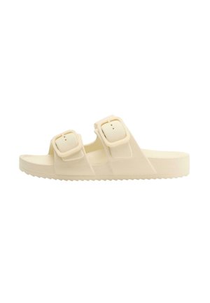Beige slide sandal with two adjustable buckle straps and a ridged sole, designed for casual wear and comfort.