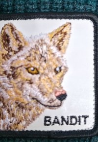 Geborduurd patch met een vosgezicht, gedetailleerde vacht in bruine en crèmekleuren, zwarte omlijning, en de tekst "BANDIT" eronder in vet zwart.