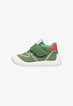 Sneaker a rete verde con suola in gomma bianca, dotata di una fascetta in Velcro verde e dettagli rossi sul tallone e sul colletto.