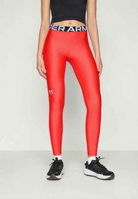 Leggings atletici rossi realizzati in tessuto elasticizzato con una fascia in vita con il logo nero di Under Armour. Texture liscia, design aderente, senza motivi aggiuntivi.