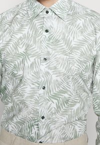 Lichtgewicht button-up shirt met een groen-witte bladerenpatroon. Accenten van donkere knopen, het heeft een klassieke kraag en een ontspannen pasvorm.