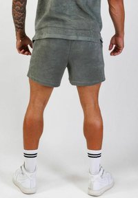 Grå fleecebyxor med en mjuk textur, sidofickor och en avslappnad passform. Matchas med vita högstövlar och randiga strumpor.