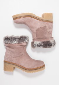 Pink suede ankle boots with a faux fur trim, rubber outsole, stacked heel, and rounded toe, featuring a smooth texture and minimal stitching.
