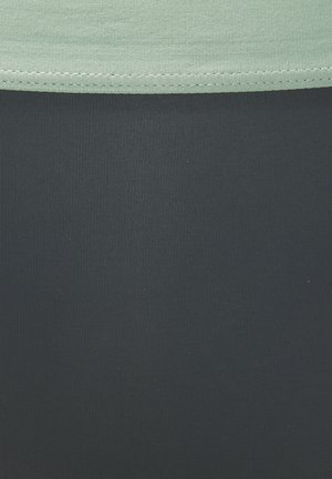 Light green top with a smooth texture, paired with dark navy bottoms featuring a ribbed surface. The stitch detailing is visible at the seam.