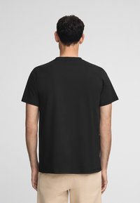 Svart bomull t-shirt med korta ärmar, rund halsringning och en avslappnad passform. Slät textur, enhetlig färg, inga synliga logotyper eller mönster.