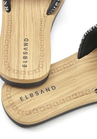 Wooden flip-flops with black fabric straps. Engraved brand name "ELBSAND" on the tan sole, detailed border pattern around the edges.
