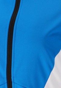 Blaues Sportjackett mit glattem Material, ausgestattet mit einem schwarzen Reißverschluss und weißen Akzenten an den Seiten. Fokus auf athletischem Design.