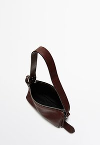 Sac en cuir marron avec une seule bandoulière, fermeture zippée et texture lisse. Présente un intérieur non doublé et un profil slim.