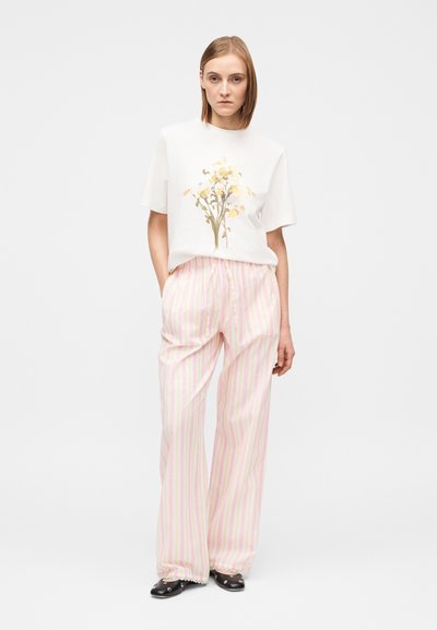 Λευκό βαμβακερό μπλουζάκι με λουλουδάτο σχέδιο, συνδυασμένο με ροζ ανοιχτόχρωμο παντελόνι φαρδιάς γραμμής με ρίγες. Το παντελόνι έχει ζωνάκι με κορδόνι στη μέση και δαντελένιο τελείωμα στο κάτω μέρος.