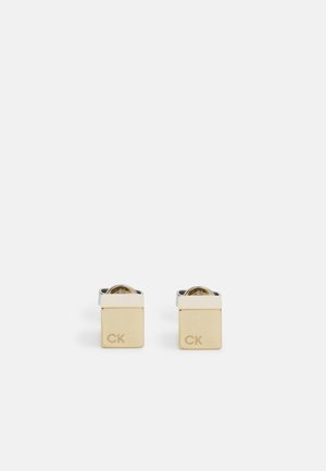 Gold- und Silberelemente in Form von Manschettenknöpfen mit quadratischem Design, graviert mit "CK," versehen mit glänzender Oberfläche und einem klaren, runden Zentrumsdetail.