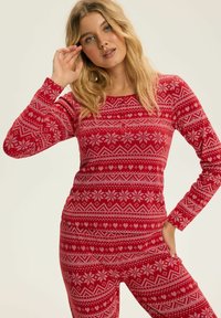 Czerwony zestaw piżamowy z długimi rękawami, okrągłym dekoltem i geometrycznym białym wzorem z sercami i płatkami śniegu na całej powierzchni.