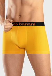 Yellow cotton boxer briefs with a black waistband featuring red text. The fabric appears smooth with a fitted design and short leg lengths.