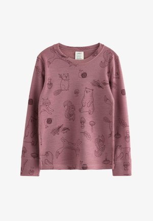 Lille barn med langt, krøllet hår står barfodet iført matchende lilla pyjamas med dyre- og naturmønstre.