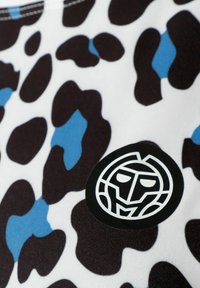 Tela de estampado animal en negro y azul con una textura suave; presenta un logo negro redondo con un diseño de cara estilizado.