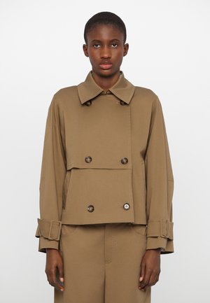 Cropped, brown, double-breasted jacket with a wide collar, large buttons, and rolled cuffs, made from a smooth, sturdy material.