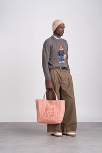 Gray sweater with fox embroidery, beige beanie, light blue shirt, tan wide-leg trousers, and a pink tote bag featuring a fox design.