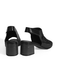 Zwarte leren schoenen met een ronde neus, slingback ontwerp en een gemiddelde blokhak met verticale ribbels. Gladde textuur met subtiele plooien.