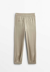 Beżowe spodnie na gumce z elastycznymi mankietami i dwiema zasuwanymi kieszeniami z tyłu, pokazane na płasko na białym tle.